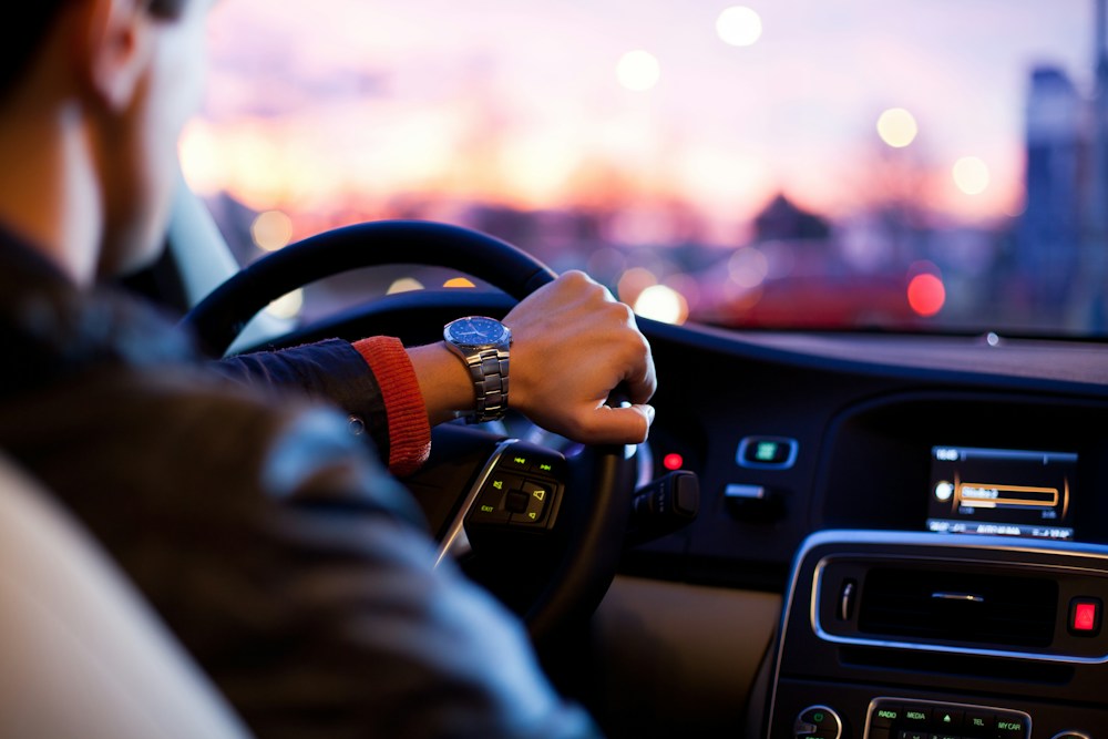 Motorista ao volante com a cidade ao fundo